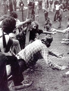 Protesters climb through the fence around the gym site in 1977.
